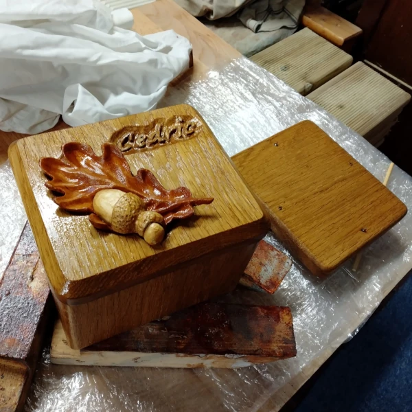 Wooden ashes casket with oak leaf and nut carving on lid